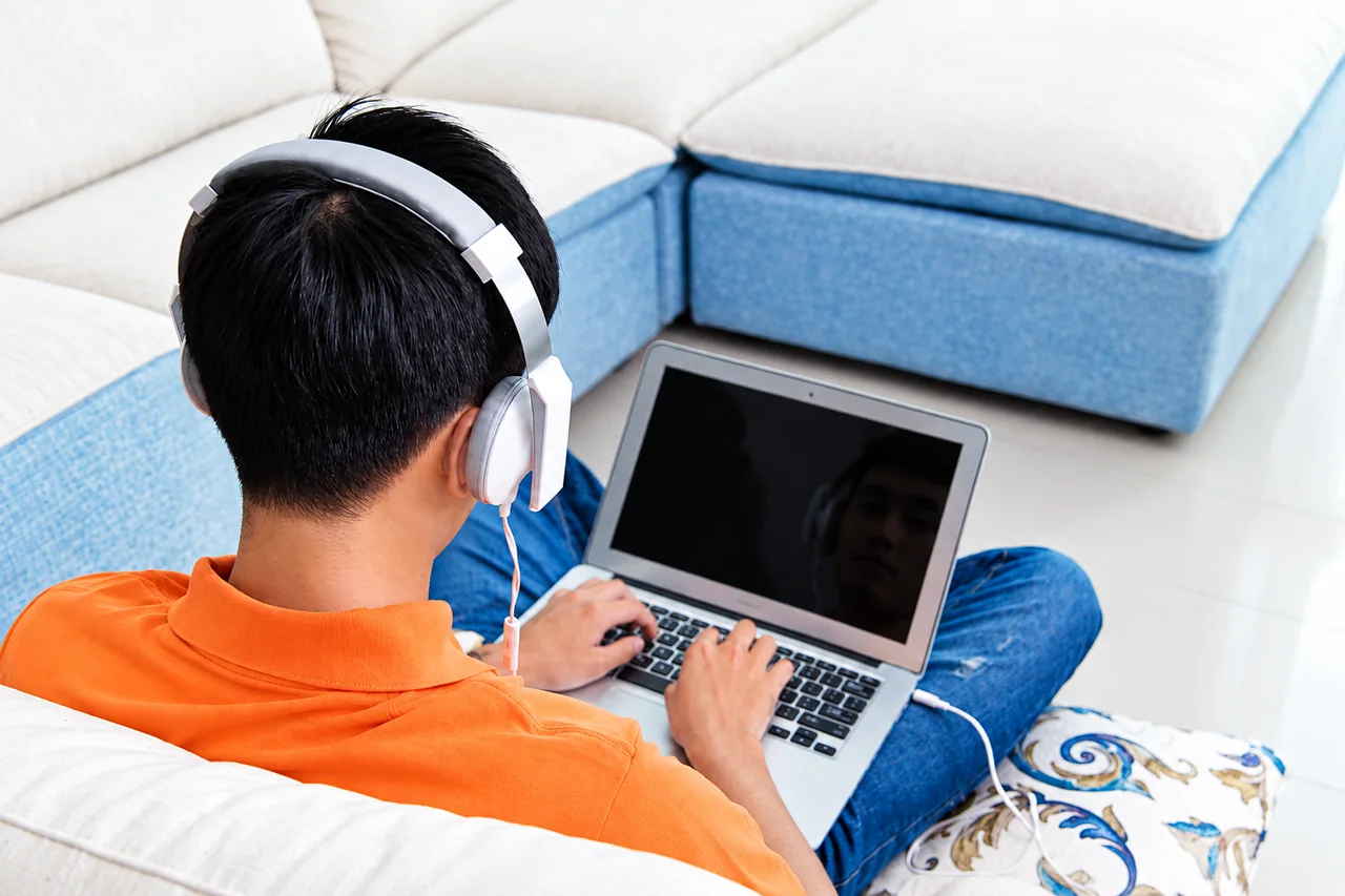 A digital employee working remotely on a laptop while wearing headphones